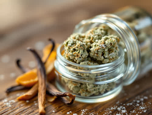 Wedding Cake hemp flower in a clear glass jar on walnut