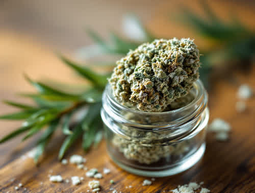 White Widow hemp flower in a clear glass jar on walnut
