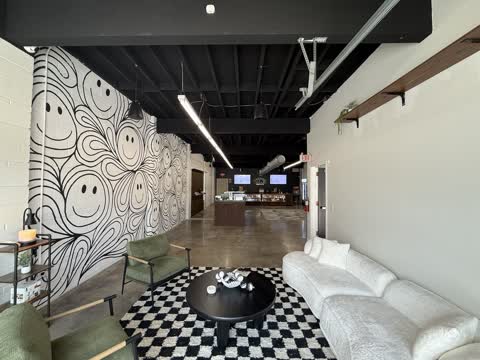 Seating lounge inside White Label Exotics with a hand-painted smiley mural, armchairs and a curved sofa.